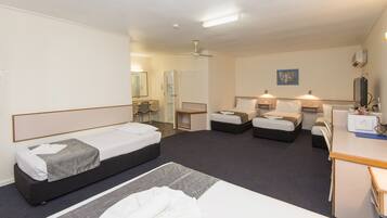 A hotel room with two single beds, a desk, a chair, and a small table.