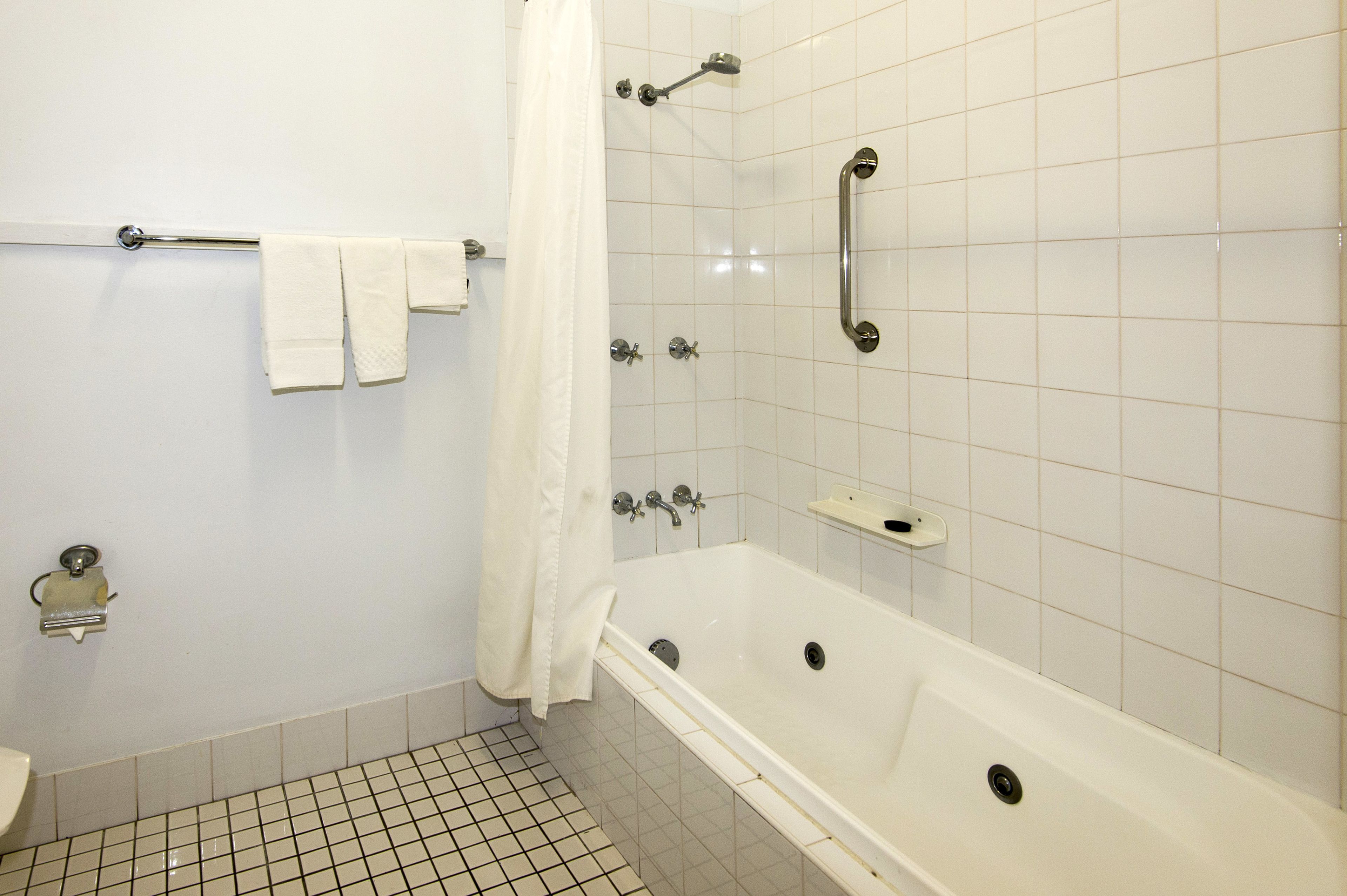 A bathroom with a white bathtub, a shower area, and a toilet.