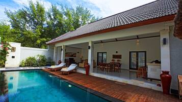 A poolside area with a covered patio, lounge chairs, and a dining area.
