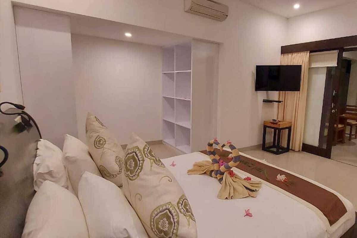 Habitación de hotel con cama, televisor, puerta corrediza de vidrio y una pequeña mesa.