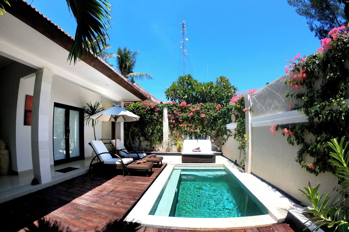 Un área de piscina privada con sillones de descanso, una pequeña mesa y una terraza de madera.