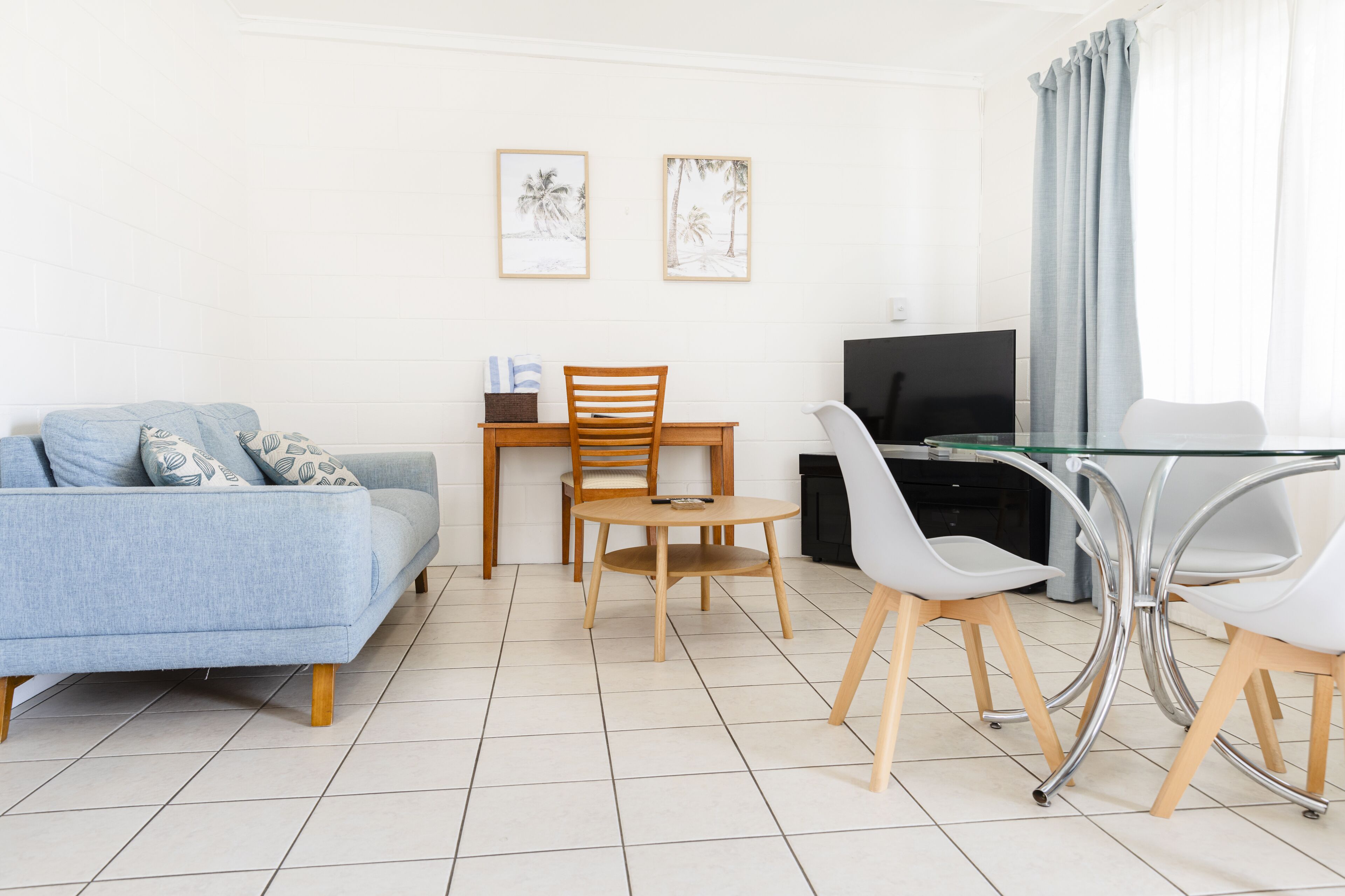 En moderne stue med sofa, spisebord med stole, fjernsyn og billeder i rammer på væggen.