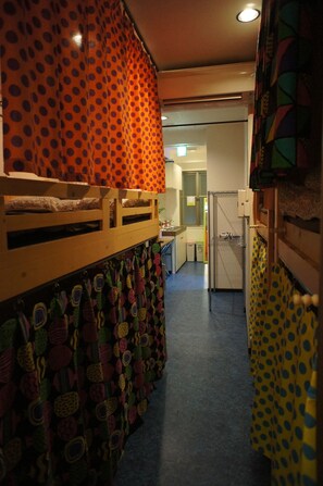 A narrow hallway with a bunk bed on the left, a kitchen area with a refrigerator and sink in the center, and a door leading to another room on the right. - Hostel BASE POINT Osaka (Osaka)