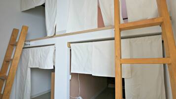 Uma cama beliche com escadas de madeira e lençóis brancos.