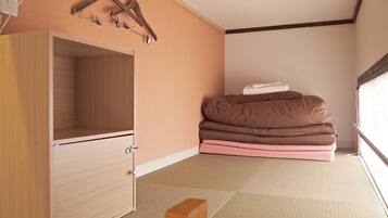 Una habitación con un armario de madera, una cama con ropa de cama marrón y rosa, y una ventana con persianas.
