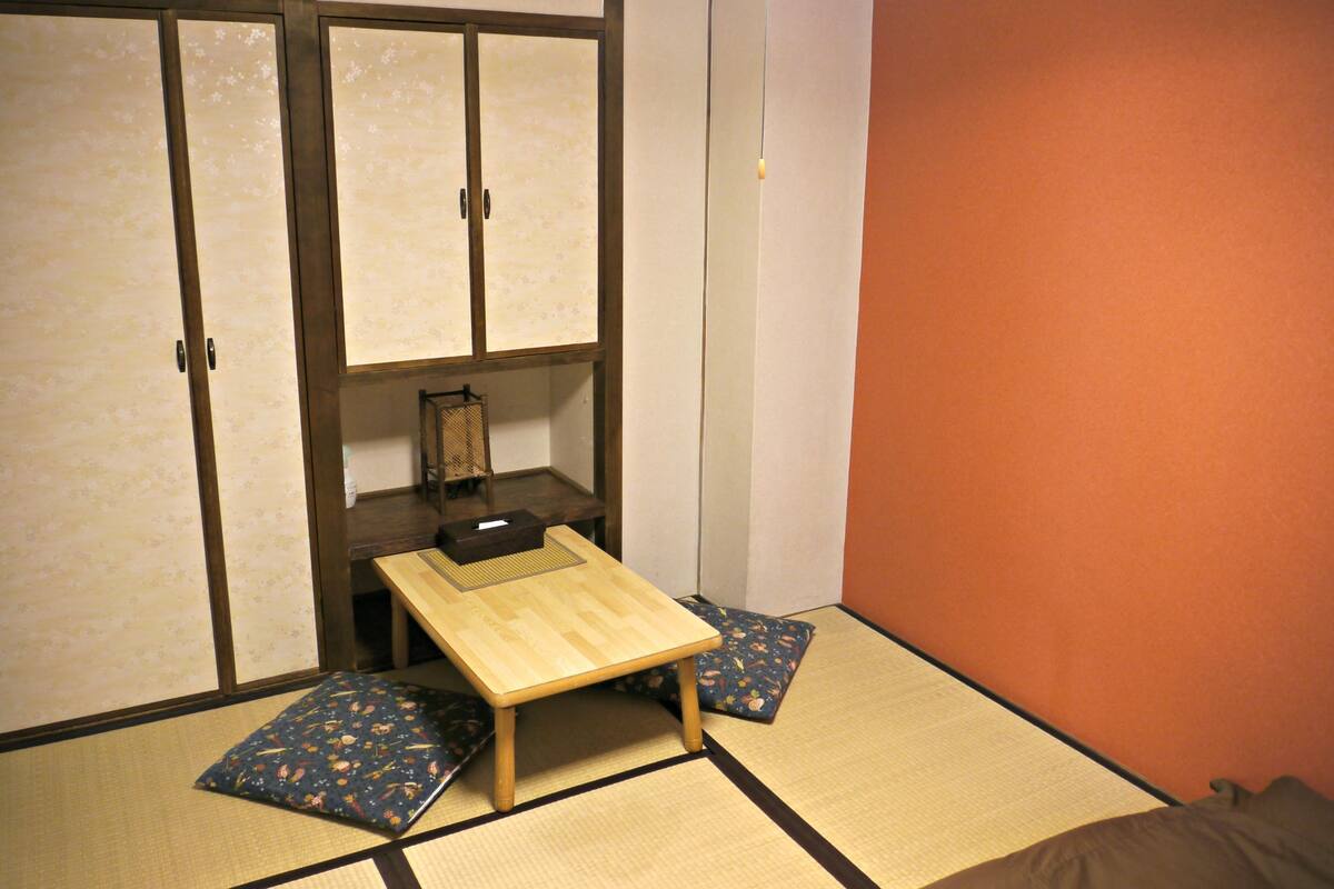 Perinteinen japanilainen huone, jossa on tatamimatto, matala puupöytä ja futon-patja.