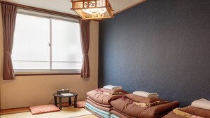 Une pièce de style japonais traditionnel, avec un sol recouvert de tatamis, un paravent en papier de riz (shoji) et un futon servant de lit.