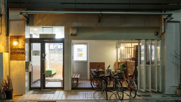 L’entrée d’un restaurant, avec une porte en verre, un vélo garé à l’extérieur et un banc en bois à l’intérieur.