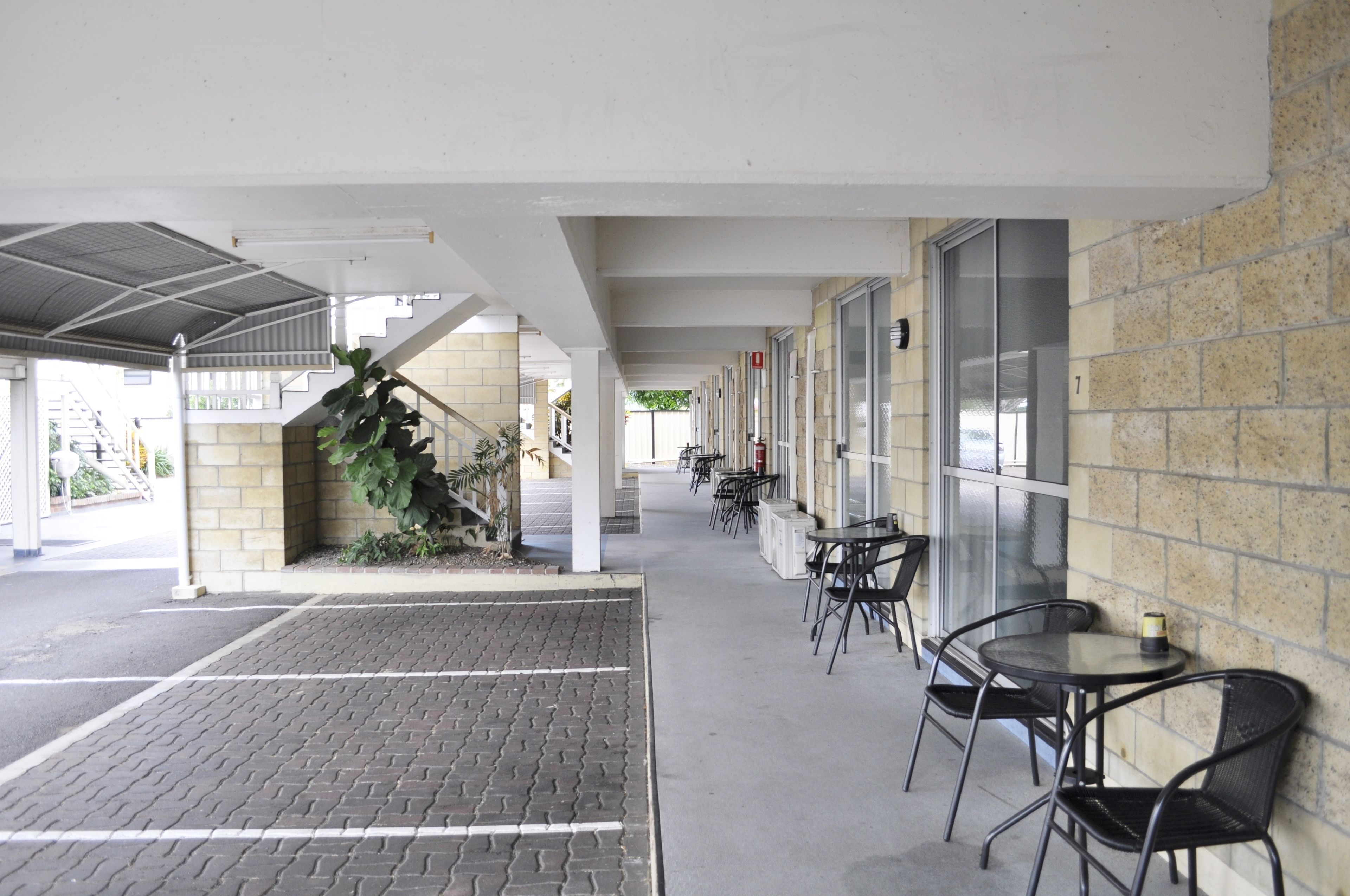 Un espacio al aire libre techado con pared de ladrillo, una escalera y varias mesas y sillas.