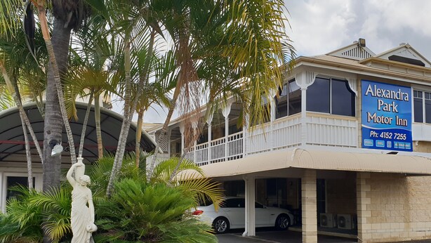 A building with a sign for 'Alexandra Park Motor Inn' and a statue in the foreground. - Alexandra Park Motor Inn (Bundaberg West)