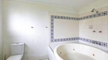 A bathroom with a toilet, a bathtub, and a shower area.