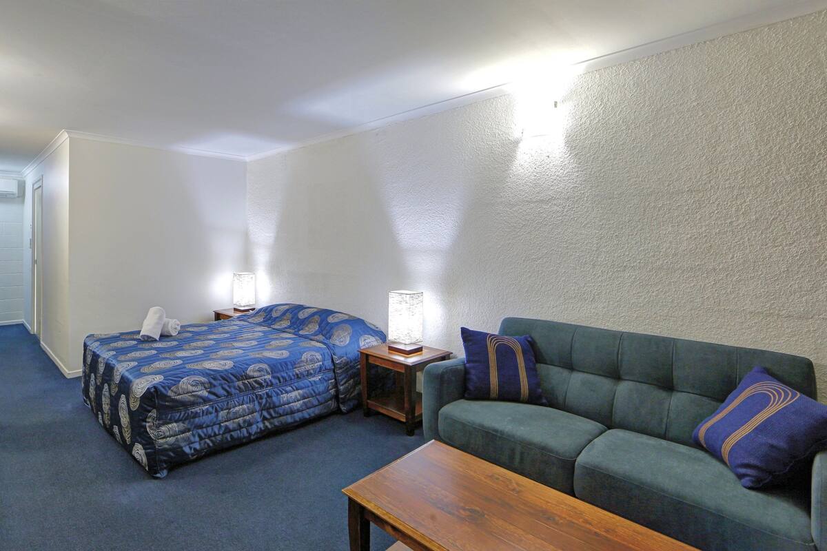 Um quarto com uma cama, um sofá e uma mesinha.