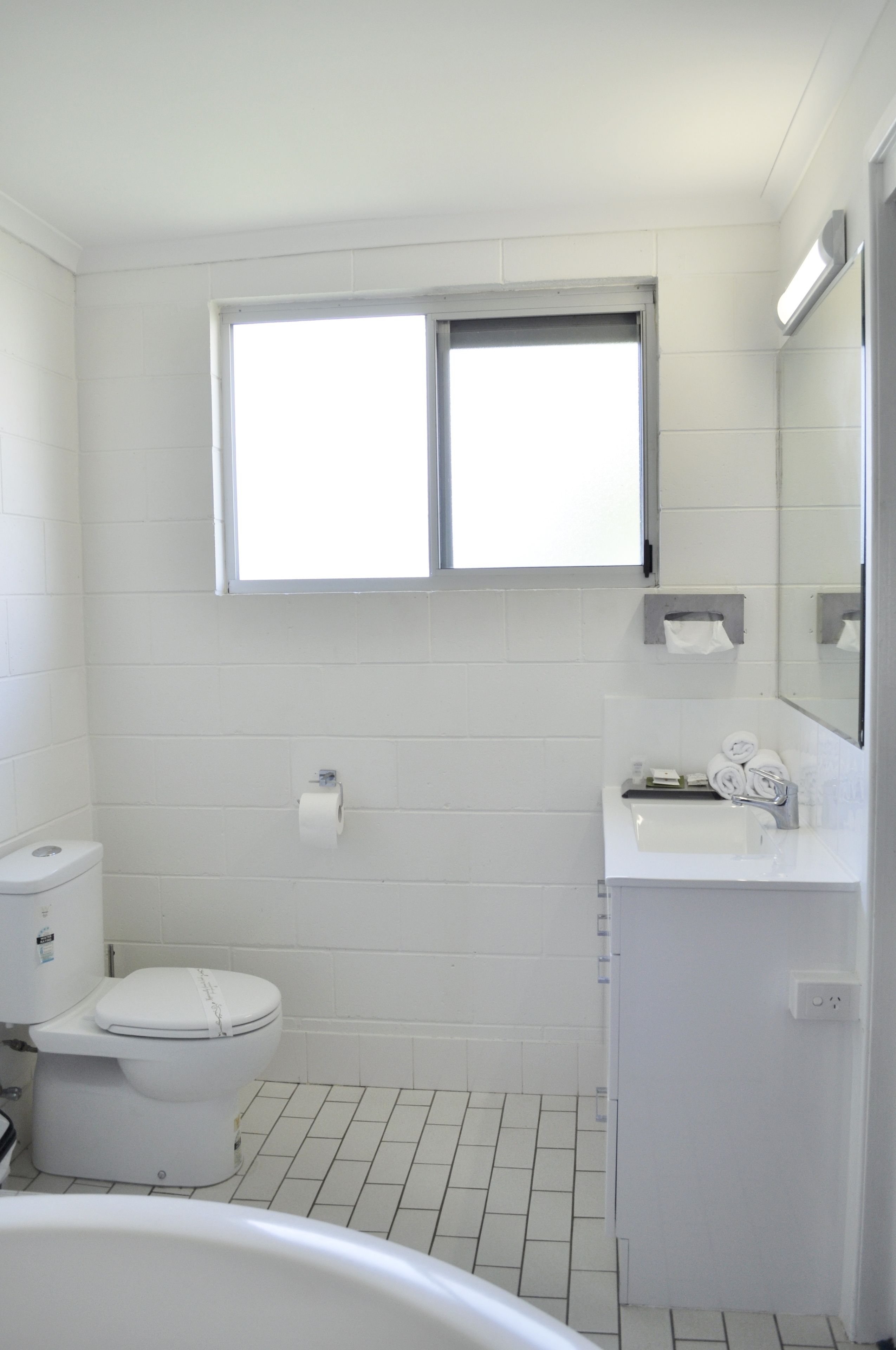 A bathroom with a toilet, sink, and window.