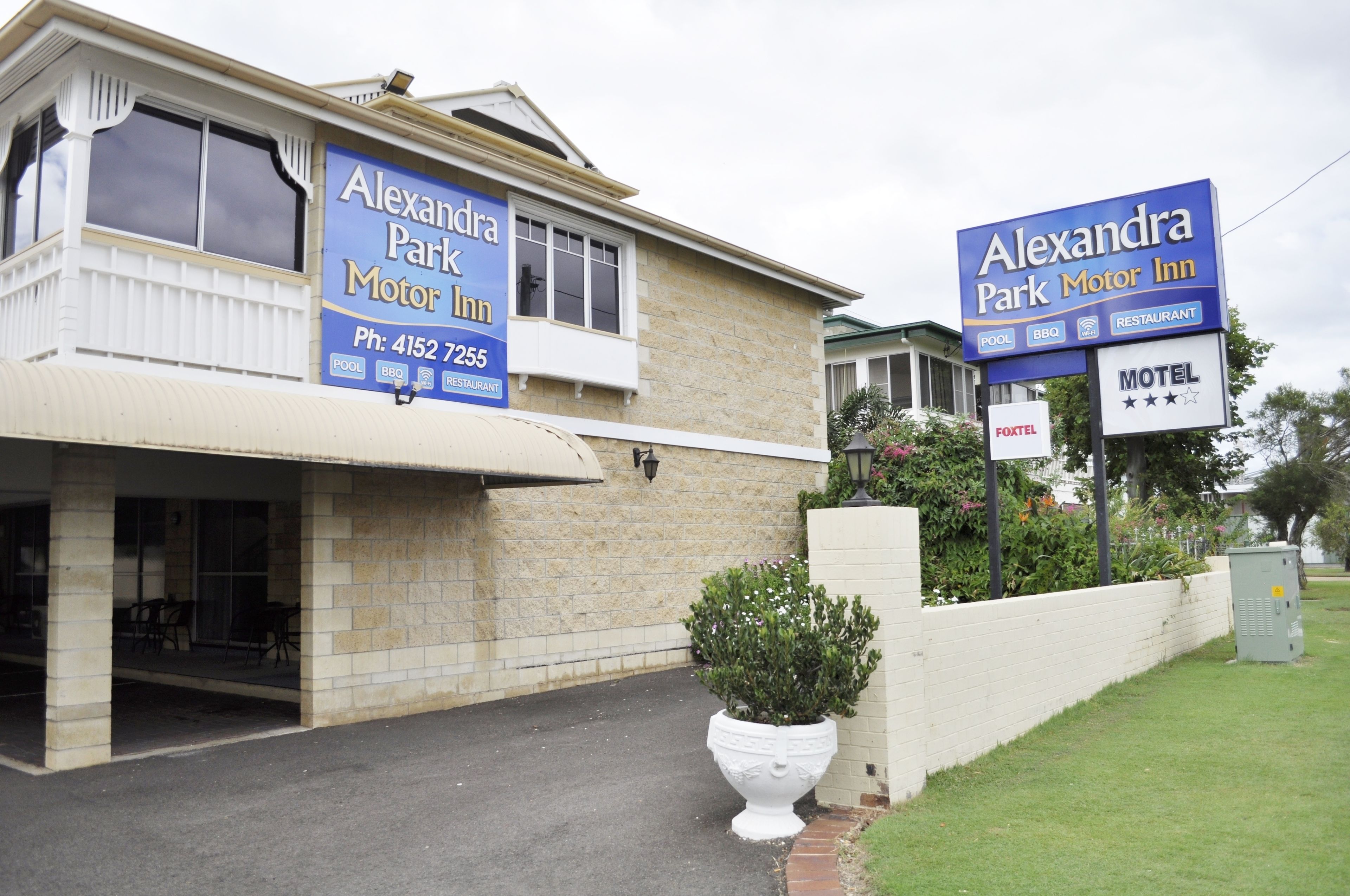 Un edificio con letreros que indican 'Alexandra Park Motor Inn' y 'Alexandra Park Motor Inn Motel'.
