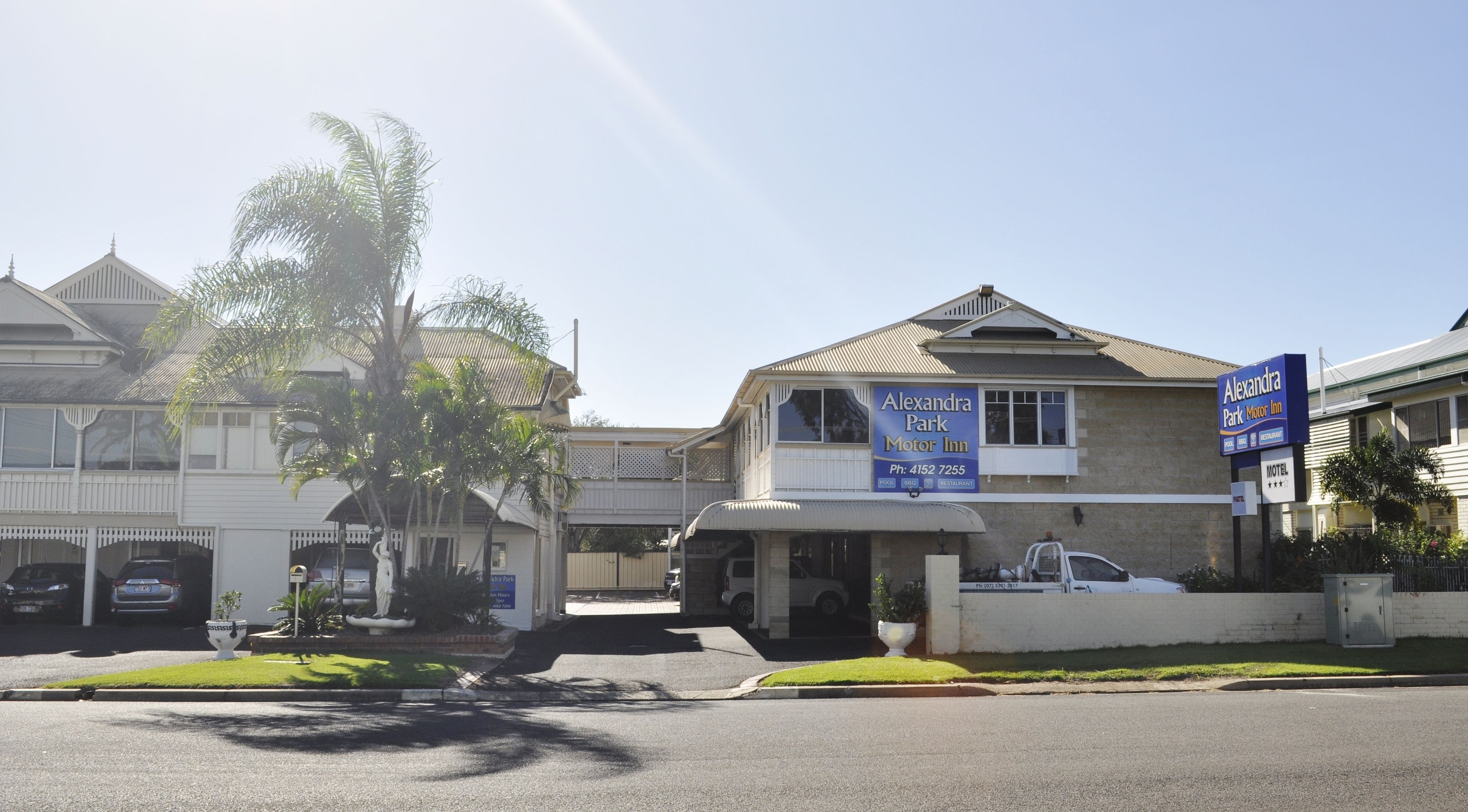 A motor inn with a signboard, a parking area, and a building with a balcony.
