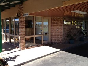A reception area with a sign indicating 'Reception' and a 'Town & Country Motor Inn' sign on the building facade. - Town & Country Motor Inn Forbes (Forbes)