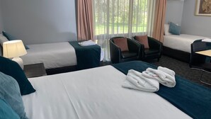 Une chambre d’hôtel avec deux lits, un bureau, une chaise et une fenêtre avec des rideaux.