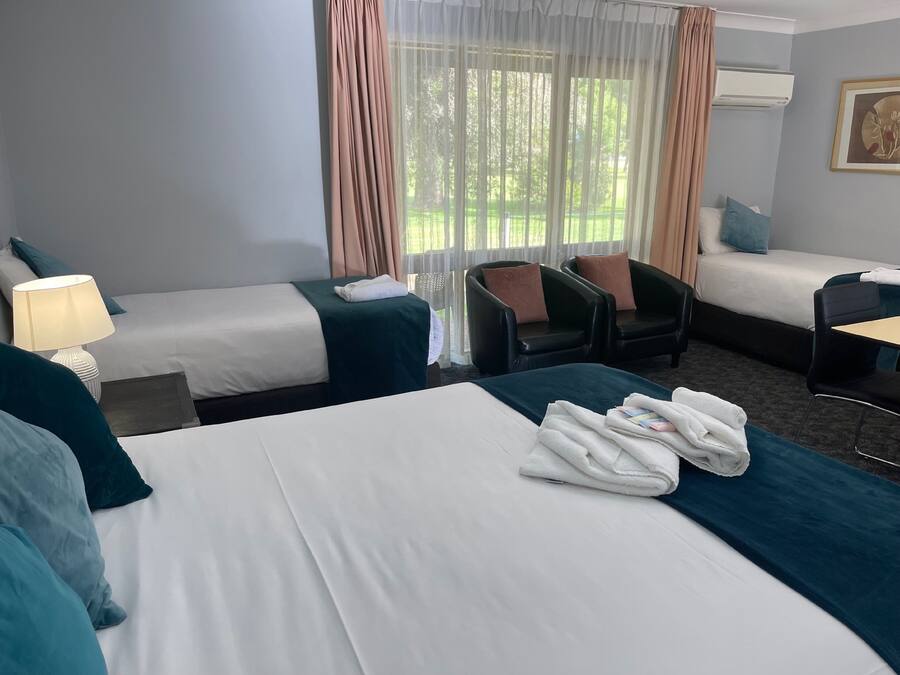 A hotel room with two beds, a desk, a chair, and a window with curtains.