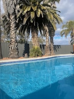 Una piscina al aire libre, sillones reclinables de piscina