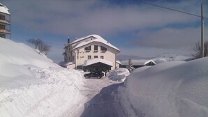 Una carretera nevada que conduce a un edificio con techo inclinado y varias ventanas.