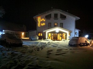 A hotel with a snow-covered driveway and a lit entrance. - Hotel LuSi (Roccaraso)