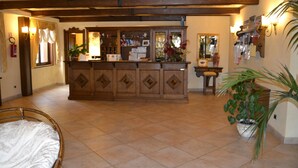 Un hall de hotel con mostrador de recepción, una cama y una planta en maceta.