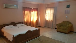 Une chambre à coucher avec un lit, des rideaux, une chaise et un tapis.