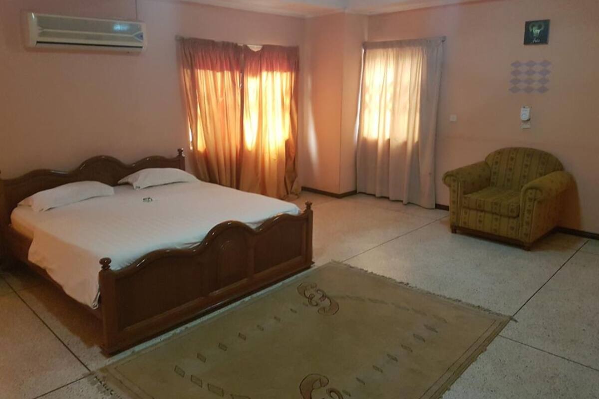 Une chambre à coucher avec un lit, des rideaux, une chaise et un tapis.