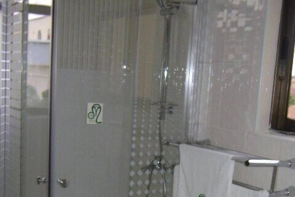 Une salle de bain avec une douche à parois de verre, un lavabo blanc et deux serviettes suspendues à un porte-serviettes.