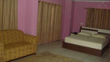 Un dormitorio con cama, sofá y cortinas.