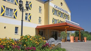 Un hotel con fachada amarilla, diseños de ventanas azules y amarillos, y un letrero que dice 'GRANDHOTEL NIEDERÖSTERREICHSISCHE HOF'.