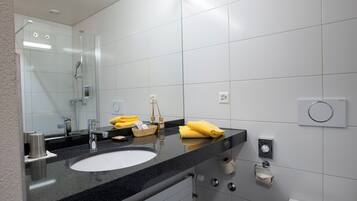 A modern bathroom with a large mirror, a sink, and a shower.