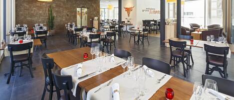 A modern restaurant with multiple dining areas, each with tables set for two.