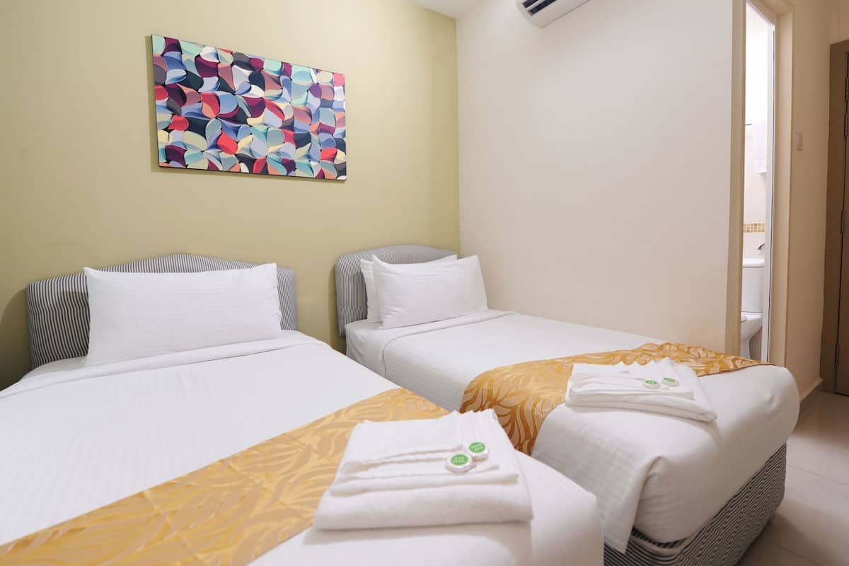 A hotel room with two beds, a colorful abstract painting on the wall, and a bathroom visible through an open door.