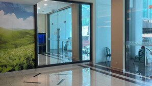 Eine moderne Lobby mit Glastüren, einem Fliesenboden und einem Landschaftsgemälde.