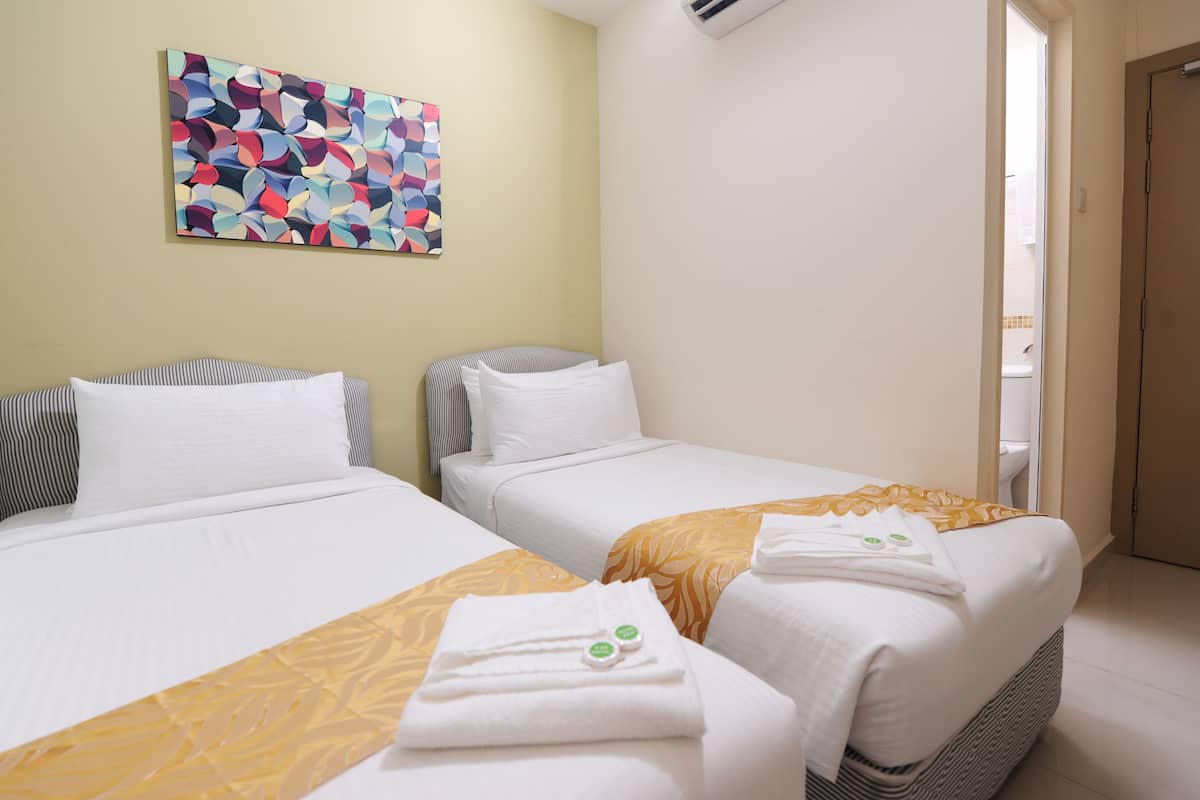 A hotel room with two beds, a colorful abstract painting on the wall, and a bathroom visible through an open door.