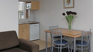 A compact living space with a kitchenette, a dining table with chairs, and a sofa.
