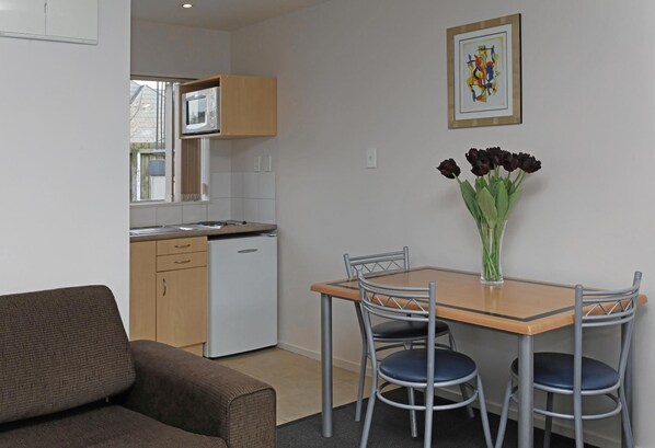 A compact living space with a kitchenette, a dining table with chairs, and a sofa.