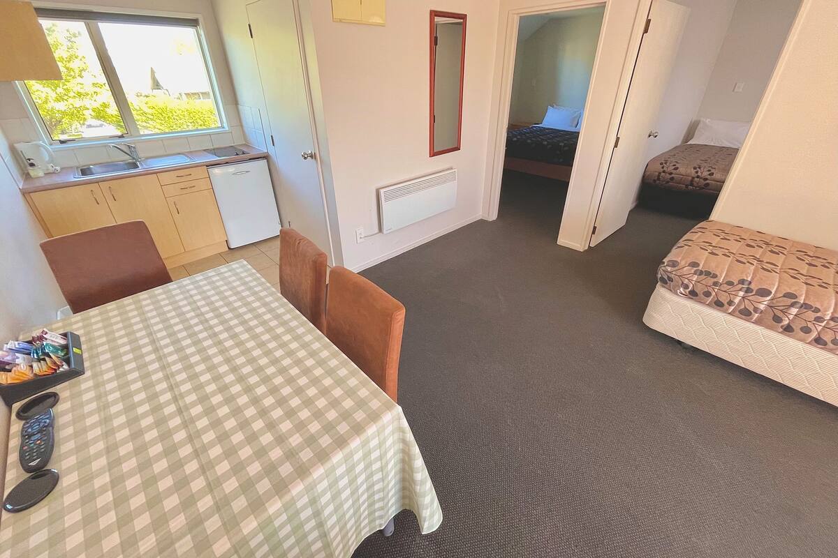 Una habitación compacta con kitchenette, una mesa de comedor, un sofá y una cama.