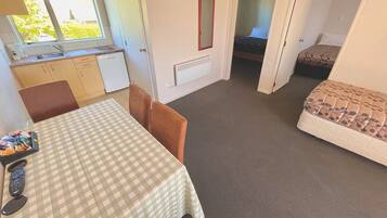 A compact room with a kitchenette, a dining table, a sofa, and a bed.