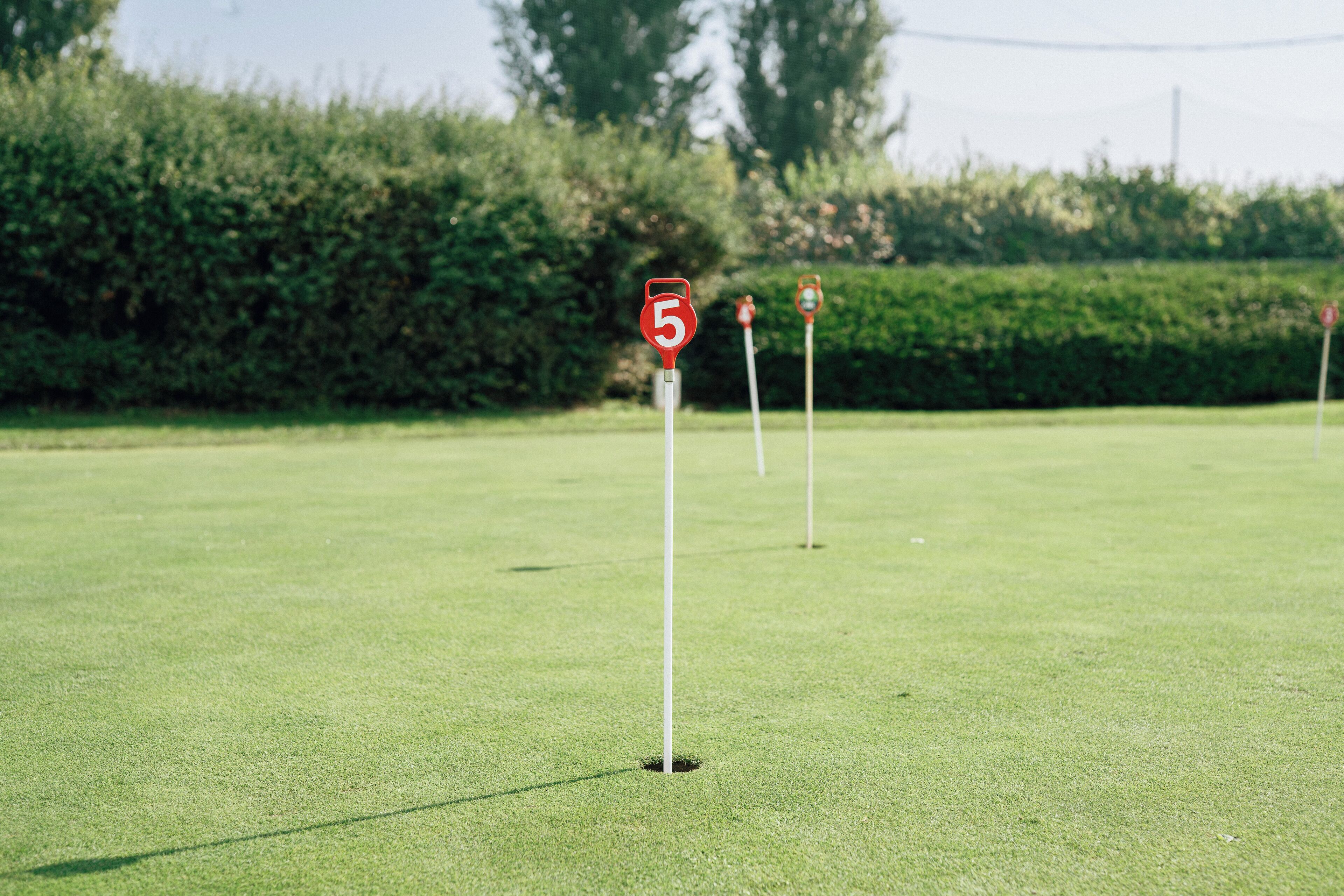 En golfbana med ett hål som är markerat med en röd flagga och siffran 5.