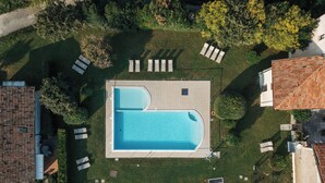 Eine Vogelperspektive eines Wohnhauses mit Swimmingpool, Liegestühlen und Garten.