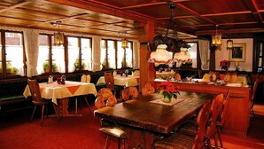 A cozy restaurant with wooden furniture, large windows, and hanging lamps. - Hotel Ochsen (Lenzkirch)
