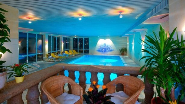 An indoor swimming pool with lounge chairs and potted plants. - Hotel Ochsen (Lenzkirch)
