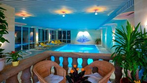 An indoor swimming pool with lounge chairs and potted plants. - Hotel Ochsen (Lenzkirch)