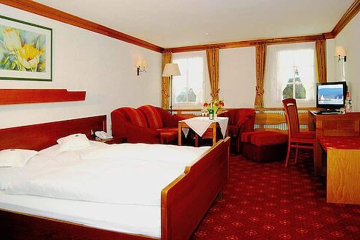 A hotel room with a bed, a desk, a chair, and a television.