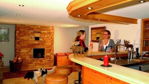 A cozy kitchen with a stone wall, wooden bar, and a dog. - Hotel Ochsen (Lenzkirch)