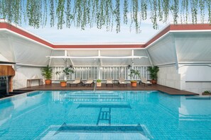 A swimming pool with lounge chairs and potted plants, surrounded by a covered area with white walls and a red roof. - The Hermitage, A Tribute Portfolio Hotel, Jakarta (Jakarta)