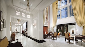 A spacious lobby with a high ceiling, a grand staircase, and a large window with curtains. - The Hermitage, A Tribute Portfolio Hotel, Jakarta (Jakarta)