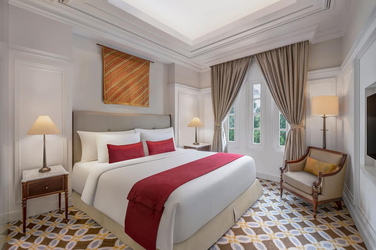 A hotel room with a large bed, two bedside tables with lamps, a chair, and a television.